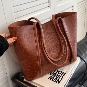 Brown crocodile texture tote bag with double handles in a minimalist urban setting