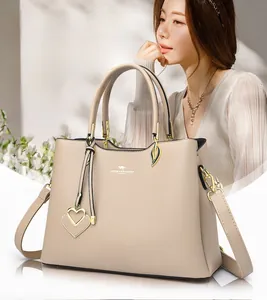 Macro detail of beige leather handbag with gold kangaroo logo and decorative heart charm