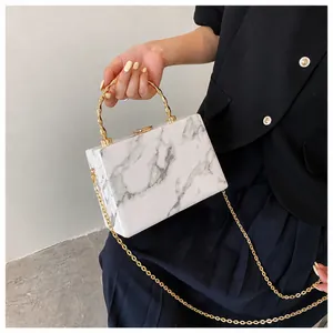 Detail of marble texture box bag with gold bamboo handle and fine metal chain strap