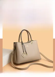 Detail view of khaki pebbled leather handbag with gold heart charm and kangaroo logo