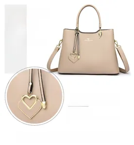 Close-up of golden heart and leaf charms on a beige textured PU leather handbag