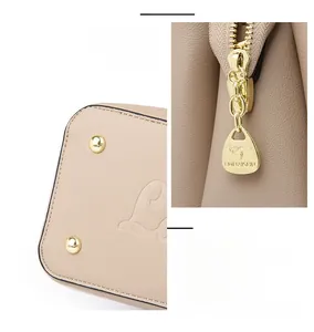 Detailed view of apricot leather texture with gold metal rivets and smooth zipper hardware