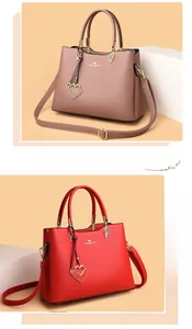 Close-up of matte leather texture and heart-shaped gold charm on the handle of the tote bag
