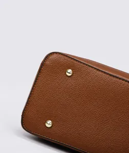 Detailed close-up of caramel lychee grain leather bottom with gold protective studs