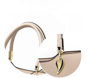 Detail view of reinforced beige leather straps and golden leaf decorative hardware on bag