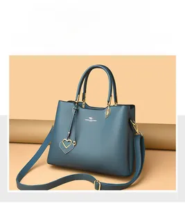 Detail showing high-quality lychee textured leather and golden heart pendant on handbag