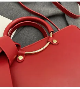 Detail of red leather bucket bag featuring elegant gold hardware and rivet accents