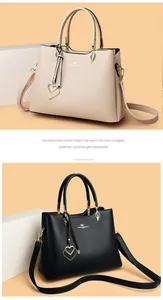 Detailed view of leather handbags with double handles, logo branding and heart pendants