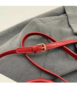 Macro detail of red lychee grain leather strap with adjustable gold metal buckle