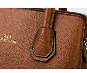 Detailed close-up of dark brown lychee grain leather with golden XTJ logo engraving