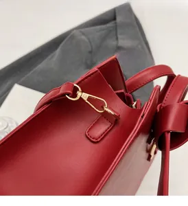 Close-up of red leather bucket bag featuring gold metal lobster clasp and fine stitching