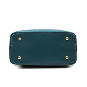 Dettaglio fondo borsa in pelle verde scuro con piedini protettivi in metallo dorato