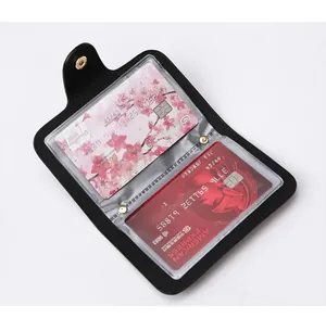 Detail of black pebbled leather card holder with gold snap button and multi-page PVC slots
