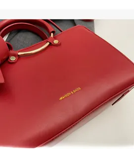 Detail of red faux leather handbag with lychee texture and gold metal hardware