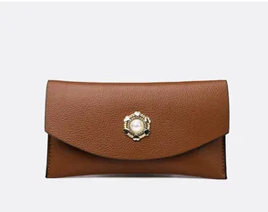 Close-up of brown textured leather wallet with gold heart and pearl clasp detail