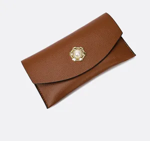 Detail of brown lychee grain leather clutch with golden petal buckle and pearl inlay