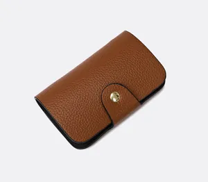 Detail of a brown lychee pattern leather card holder with a gold snap button closure