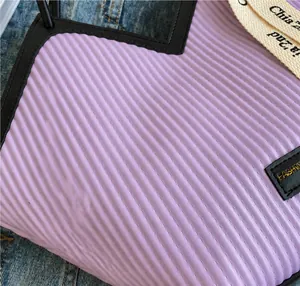 Detailed view of lavender purple pleated fabric with black leather trim and branding