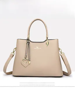 Front view of khaki handbag with heart pendant and adjustable leather shoulder strap
