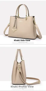 Detail view of khaki handbag featuring golden heart charm and adjustable shoulder strap