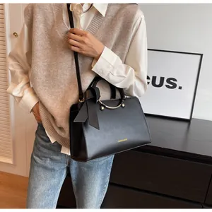 Detail of elegant black leather bucket bag with metal handle and decorative side bow