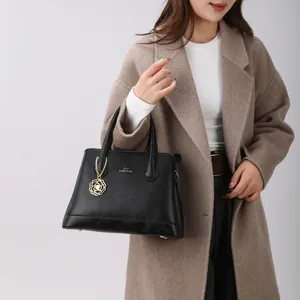 Black lychee leather tote bag with gold hardware and rose pendant held by a model