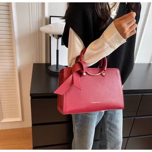 Detail of red leather bucket bag featuring a large ribbon bow and gold-tone hardware