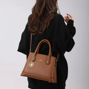 Brown lychee leather tote bag with gold rose pendant and adjustable shoulder strap
