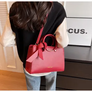 Detailed view of a red textured leather bucket bag featuring a bow and gold logo