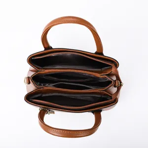 Brown leather tote bag with three compartments and gold hardware in a top-down view