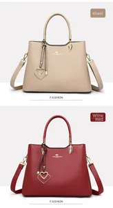 Detail view of khaki and wine red leather handbags with heart pendants and shoulder straps