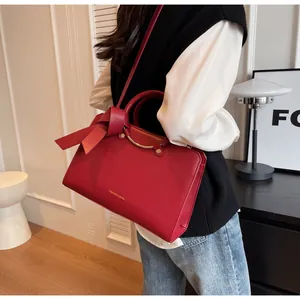Detail view of red bridal bucket bag with gold handle and decorative bow on its side