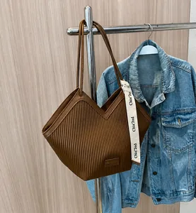 Detailed view of dark brown pleated canvas tote bag with V-shaped cut and chic ribbon