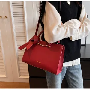 Fashionable red bucket bag featuring gold metal handle and elegant bow detail decoration