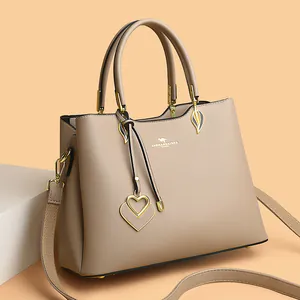Khaki pebbled leather handbag with kangaroo logo and heart charm on a pedestal
