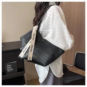 Detail view of black pleated canvas tote bag with woven strap on a model shoulder