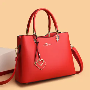 Red lychee grain leather handbag with gold hardware and heart charms in a side view