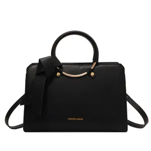 Matte black bucket bag with circular handles and elegant bow tie decoration