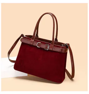 Detail of burgundy frosted tote bag with brown leather strap and silver buckle