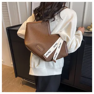 Brown canvas tote bag with V-shaped opening and decorative side straps shown on a model