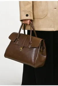 Detail view of large brown leather tote bag with elegant gold metal buckle and dual handles