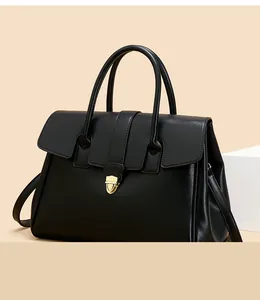 Detail of black leather tote bag showing gold lock buckle and dual top handles