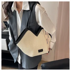 Detail of pleated beige tote bag with black trim and side decorative brand strap