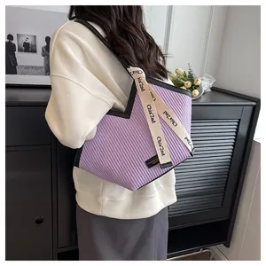 Detail showing purple pleated PU leather tote bag with branded ribbon and fashion label