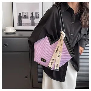 Detail of purple pleated tote bag with black leather trim and printed canvas strap detail