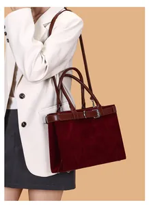 Close-up of burgundy suede tote bag with leather belt detail worn with white blazer