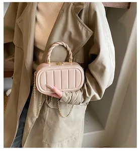 Close-up of beige box bag with vertical textured patterns and gold chain strap detail