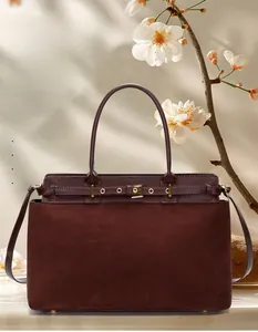 Detail of burgundy leather tote bag with matte texture and metallic buckle accents