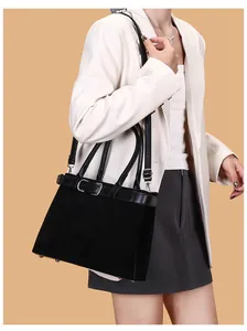 Detail of matte suede texture with leather belt and silver buckles on a black tote bag