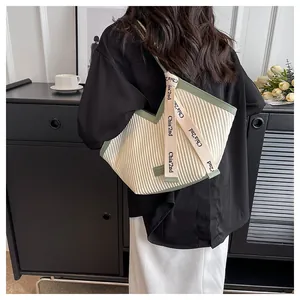 Detail of pleated tote bag featuring cream base with vintage green trim and branded strap